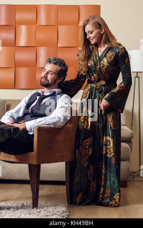 Immagine di uomo elegante su una sedia e con i capelli lunghi ragazza Foto Stock