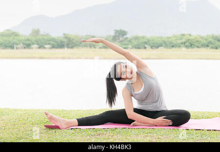 Asian giovane donna facendo yoga pratica sulla salute park sfondo - concetto di vita sana e naturale equilibrio tra il corpo e lo sviluppo mentale Foto Stock