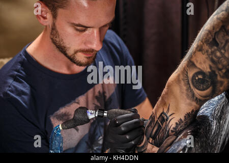 Close up tattoo artist dimostra il processo per ottenere il nero tattoo Foto Stock