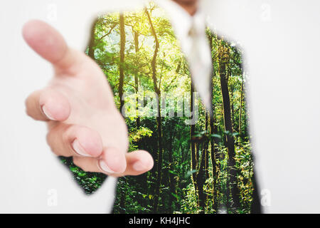 La doppia esposizione, imprenditore stretching di mano in mano scuotere con verdi alberi nella foresta. eco friendly e business sostenibile Foto Stock
