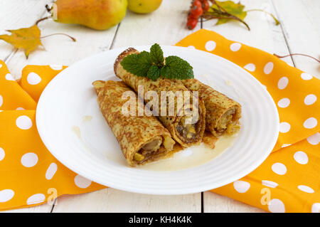 Fragranti frittelle dolci con pere caramellate su una piastra bianca. Foto Stock