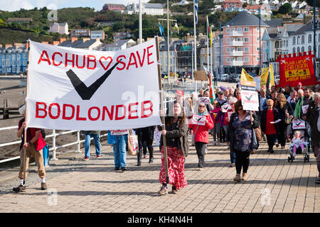 Achub / Salva bodlondeb marcia di protesta e un gruppo di persone di tutte le età in marcia attraverso le strade di aberystwyth Wales UK, portante welsh bilingue Inglese/banner, per protestare contro il ceredigion County council piani per chiudere bodlondeb, il locale la casa di cura per gli anziani, nel suo ultimo round di finanziamento di bilancio tagli. 16 settembre 2017 Foto Stock