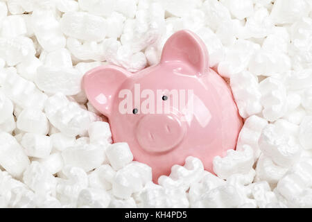 Piggybank e noccioline di polistirolo sullo sfondo Foto Stock