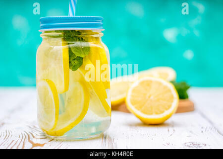 Le banche con manici con limonata a freddo su un bianco sullo sfondo di legno. i limoni Foto Stock