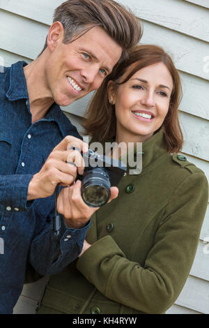 Ritratto di un attraente, di successo e Felice uomo di mezza età e la donna giovane assieme al di fuori di scattare fotografie con una fotocamera digitale Foto Stock