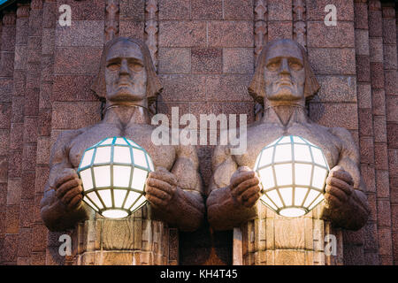 Helsinki, Finlandia. vista notturna di due coppie di statue tenendo le lampade sferiche su ingresso a Helsinki la stazione ferroviaria centrale. La sera o la notte il Foto Stock