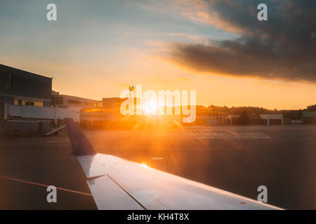 Sole che splende su aiport. vista dall'aereo aereo finestra Piano luminoso raggi del sole al tramonto sunrise. Foto Stock