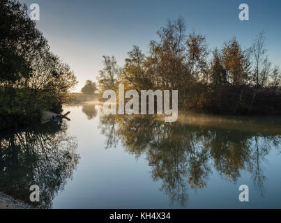 La mattina presto luce su Cadman's Pool, nella nuova foresta, mostra i colori dell'autunno di alberi ed arbusti riflessa nelle acque calme, Hampshire, Regno Unito Foto Stock