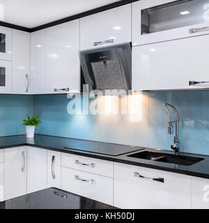 Cucina moderna con mobili bianchi e piano di lavoro nero Foto Stock