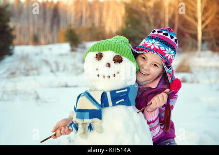 Capretto felice giocando con il pupazzo di neve Foto Stock