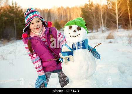 Capretto felice giocando con il pupazzo di neve Foto Stock