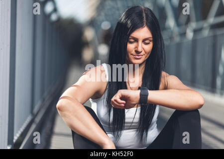 Città allenamento. bella giovane donna con una smartwatch formazione in un contesto urbano Foto Stock