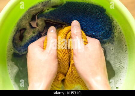 Mani femminili il lavaggio di vestiti di colore nel bacino Foto Stock