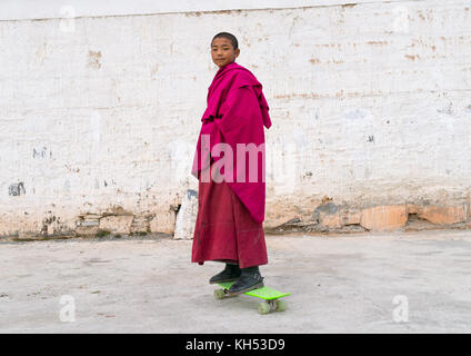 Giovane monaco tibetano su uno skateboard nel monastero Lhachub, provincia di Gansu, Lhachub, Cina Foto Stock