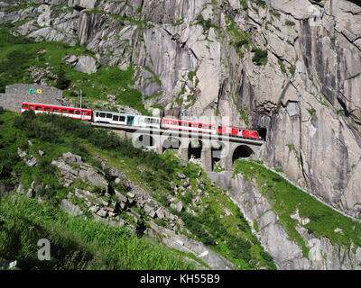 ANDERMATT, Svizzera Europa su luglio 2017: Express San Gottardo treno su Teufelsbruecke, Devil's ponte ferroviario e tunnel, alpi svizzere, alpine rocky Foto Stock