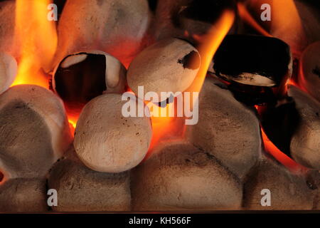 Chiusura del gas carboni di fuoco con giallo arancione fiamme, incandescente arancione e con la fuliggine su due dei carboni ardenti. Foto Stock
