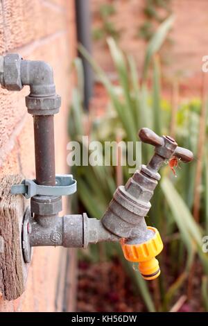 All'aperto il rubinetto dell'acqua sulla parete della cucina con tubo flessibile giallo connettore collegabile. Foto Stock