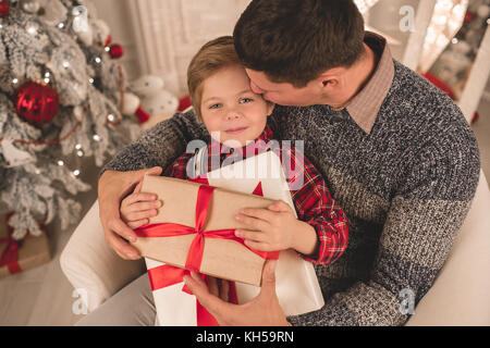 Padre e figlio di unwrapping presenta sulla sera di Natale Foto Stock