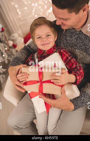 Padre e figlio di unwrapping presenta sulla sera di Natale Foto Stock