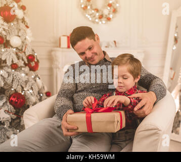 Padre e figlio di unwrapping presenta sulla sera di Natale Foto Stock