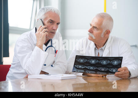 Due consulenti senior holding xray, uno parlando al telefono Foto Stock