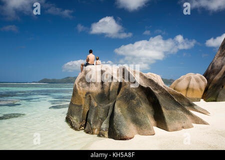 La Seychelles, La Digue, L'Union Station Wagon, turisti sat sulle rocce ad Anse Source d'Argent beach Foto Stock