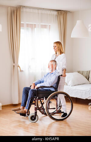 Infermiere e senior uomo in sedia a rotelle durante home visita. Foto Stock