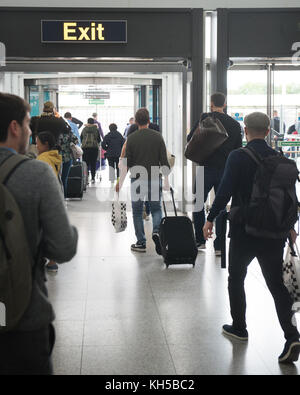 Le persone che lasciano l'aeroporto di Stansted tramite segnale di uscita dagli arrivi internazionali Foto Stock