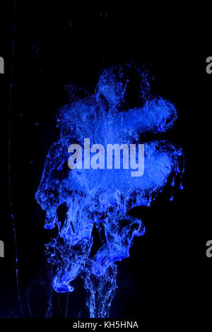 Colorante blu in acqua creando un colorato disegno astratto isolato su sfondo nero Foto Stock