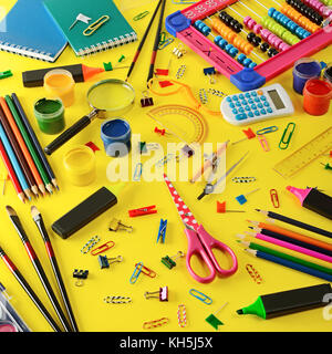 Grande assortimento di forniture scolastiche su sfondo giallo. vista dall'alto. Foto Stock