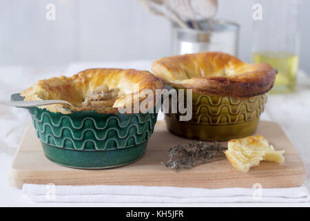 Torta di pollo con funghi cotti in singole forme ceramiche. stile rustico, il fuoco selettivo. Foto Stock