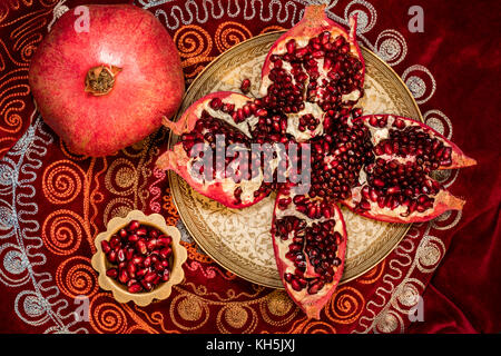 Vista superiore dei pomodori pelati melograno e grani di ruby in una ciotola sulla tovaglia orientali Foto Stock