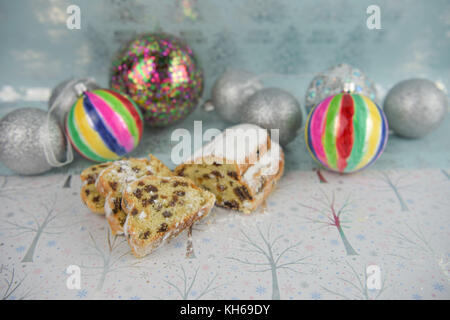 Gastronomia natalizia fotografia immagine della tradizionale torta rubati con tree baubles di decorazione in colori luminosi in bianco lucido e luce sfondo blu Foto Stock