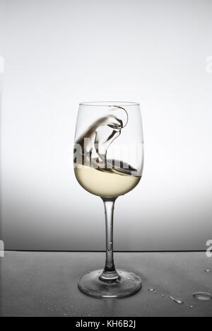 Spruzzare con il vino bianco in un bicchiere Foto Stock