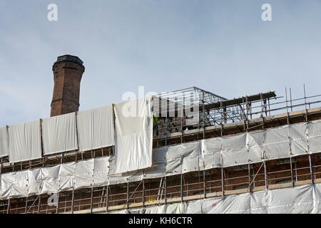 Operai che rimuovono i fogli da un tetto temporaneo al Murrays' Mills Complex, in fase di conversione in appartamenti, Ancoats, Manchester, Inghilterra, Regno Unito Foto Stock