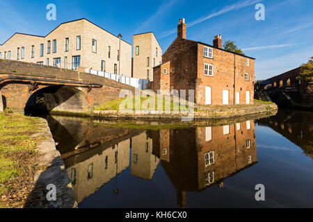 Il quartiere di Islington Wharf Mews blocchi di appartamenti e da un ex detentore di bloccaggio's cottage riflessa nell'Ashton Canal, Ancoats, Manchester, Inghilterra, Regno Unito Foto Stock