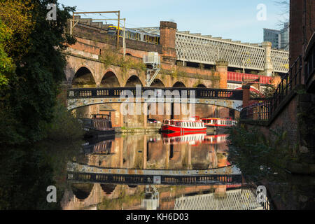 Una passerella, Vittoriano viadotti ferroviari e battelli riflessa nella Bridgewater Canal a Castlefield, Manchester, Inghilterra, Regno Unito. Foto Stock