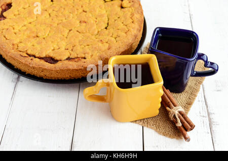 Due belle coppe (blu scuro e giallo) con caffè, tè e pane appena sfornato dolci fatti in casa con confettura di albicocca. Foto Stock