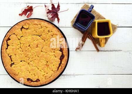 Due belle coppe (blu scuro e giallo) con caffè, tè e pane appena sfornato dolci fatti in casa con confettura di albicocca. La vista superiore Foto Stock