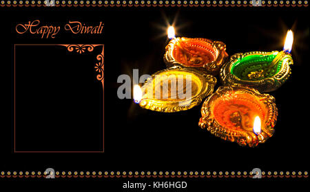 Diwali colorato di creta che brucia le lampade diya isolato in uno sfondo scuro con spazio per il contenuto dei messaggi di saluto Foto Stock