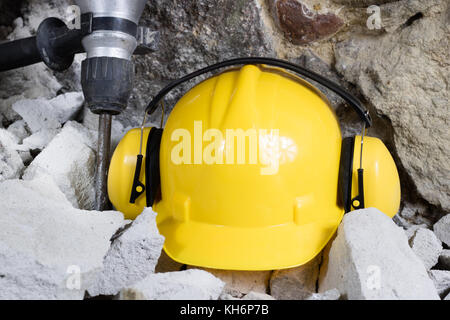 Demolizione di pareti. martello elettrico casco e protezione udito giacenti sulle macerie mattoni vecchi e rimodellata parete edilizia. grunt sullo sfondo Foto Stock