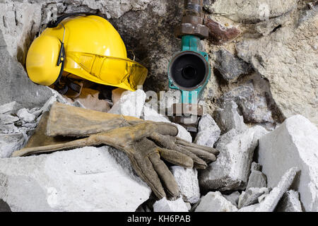 Demolizione di pareti. martello elettrico casco e protezione udito giacenti sulle macerie mattoni vecchi e rimodellata parete edilizia. grunt sullo sfondo Foto Stock