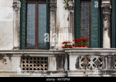 Fiori di colore rosso su un balcone vintage a venezia, Italia Foto Stock