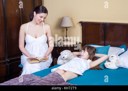 La Madre insegna a sua figlia di leggere. le relazioni tra genitori e figli, l'istruzione, la vita comoda. studio shot Foto Stock