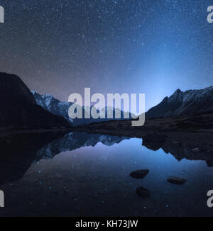 Notte stellata in Nepal. Incredibile scena notturna con le montagne e il lago. Paesaggio con alte rocce a picco innevato e il cielo con le stelle si riflette in acqua in Foto Stock