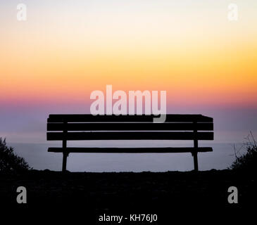 Vecchia panca di legno che si affaccia su un colorato tramonto sopra il mare di nebbia orizzonte Foto Stock