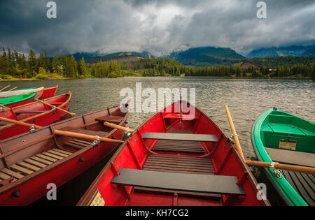 Barche colorate sul dock circondato montagne Foto Stock