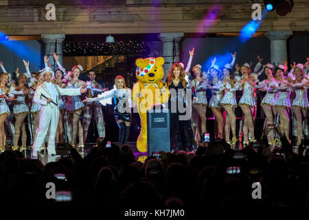 Covent Garden, Londra, Regno Unito, 14 novembre 2017. Le luci natalizie Covent Garden 2017 sono accese da Pudsey con ospiti speciali, la cantante Kylie Minogue e il designer Charlotte Tilbury. Le celebrazioni festive includono spettacoli dal famoso musical West End 42nd Street che si esibisce con i numeri dello spettacolo. Pudsey e i suoi ospiti speciali Kylie accendono le luci in collaborazione con BBC Children in Need quest'anno. La Piazza ospita il più grande albero di Natale di Londra, selezionato a mano. Credit: Imageplotter News e Sports/Alamy Live News Foto Stock