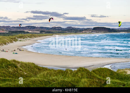 Il kitesurfing uomini in azione sul tramonto burrascosa serata al brusand beach, Norvegia. Foto Stock