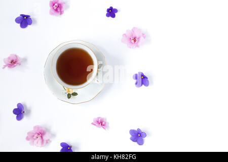 Tazza di tè e la filiale di piccoli fiori di colore rosa sul tavolo bianco. Foto Stock